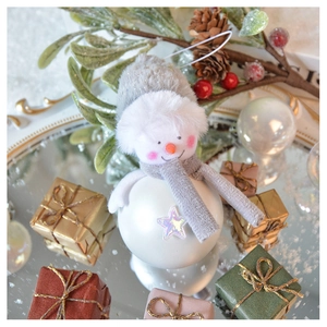 Close-up of a festive snowman ornament with grey plush hat among holiday gift boxes