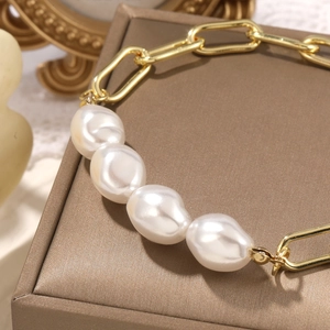 Detail of baroque pearl bracelet with chunky gold rectangular link chain on a box