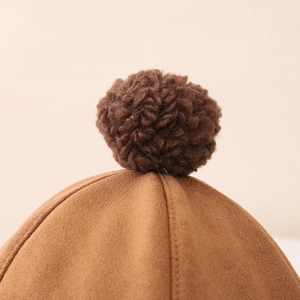 Detailed macro view of the brown faux suede material and spiral curly pompom on top