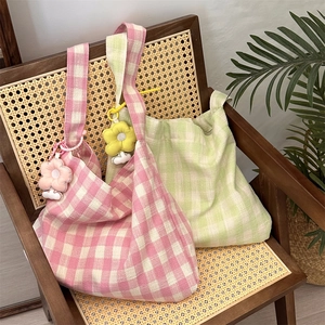 Detail of checkered canvas tote bags with plush flower charms on a rustic chair