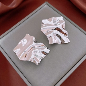 Detailed macro view of silver geometric crinkle earrings with polished metallic texture