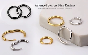 Three-color hoop earrings in gold, silver, and black displayed on minimalist stone props