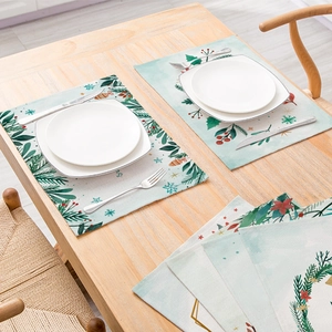 Christmas botanical placemats with green leaves and red berries on a wooden table