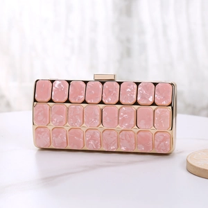 Detail of pink acrylic evening clutch featuring marble texture tiles and gold metal frame