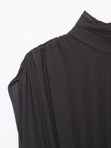 Détail d'une robe sans manches en velours noir avec col à volants et texture de mousseline