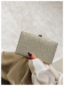Detail of gold glitter clutch bag with herringbone pattern held by a model for gala events