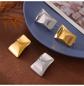 Detailed view of rectangular 18K gold and silver stud earrings on a ceramic dish