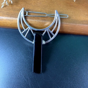 Detailed view of crescent moon hair clip with geometric frame and black crystal stone