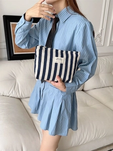 Blue and white striped canvas toiletry bag with black handles held by a model