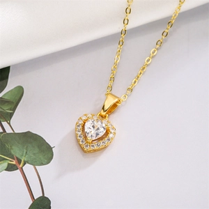 Makroaufnahme einer goldenen Herzhalskette mit funkelndem Kristall und feiner Gliederkette