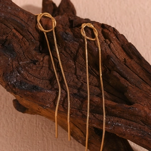 Elegant 18K gold plated snake chain tassel earrings hanging on rustic wood decor