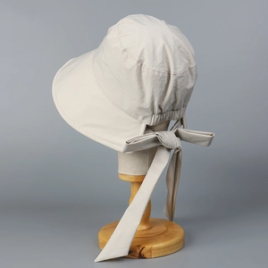 Detail of elegant cream sun hat showing back bow tie design and split brim on wooden stand