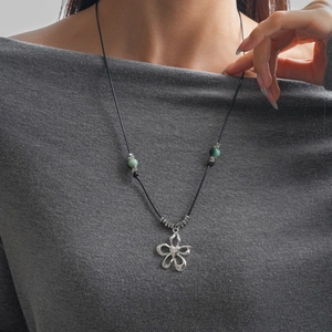 Détail du collier en corde cirée avec pendentif fleur argenté et perles en céramique
