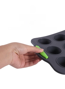 Close-up of green non-slip silicone handle on a gray muffin baking mold for heat protection