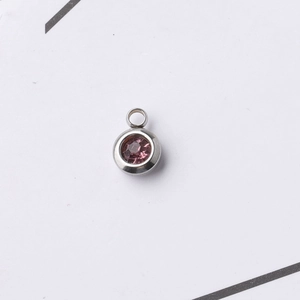 Macro view of a 6.5mm stainless steel pendant charm featuring a pink birthstone