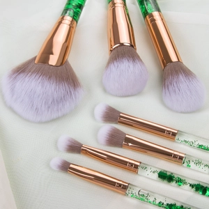 Detailed view of makeup brushes with rose gold ferrules and green liquid glitter handles