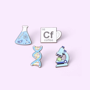 Flat lay detail of science enamel pins featuring DNA, microscope, and chemical flasks