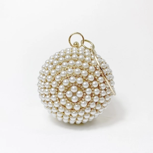 Close-up of spherical evening bag featuring white pearls and sparkling rhinestones