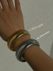 Detailed view of 20mm wide gold and silver textured ribbed bangle bracelets on wrist