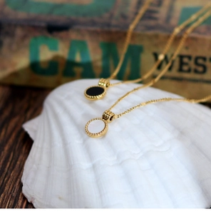 Detail of round shell and black onyx pendants on 18K gold plated stainless steel necklaces