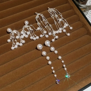 Detailed close-up of pearl drop earrings with crystal tassels on a velvet jewelry tray