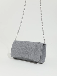 Detailed macro view of silver glitter fabric texture and fine metal chain on party clutch