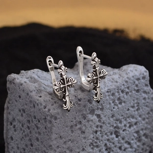Vintage S925 silver gothic cross and fleur-de-lis stud earrings on textured rock