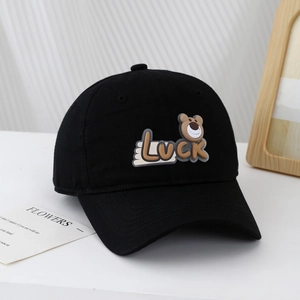Close-up of black cotton baseball cap featuring luck bear patch and embroidered air holes