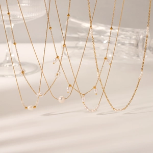 Detail view of gold-plated stainless steel necklaces with freshwater pearls and floral charms