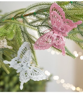 Detailed view of pink and silver glitter butterfly ornaments on green pine branches