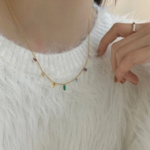 Close-up of a 14K gold plated necklace featuring colorful cubic zirconia on a model