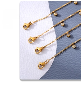 Close-up of golden beaded anklets with zircon charms and secure lobster clasp detail