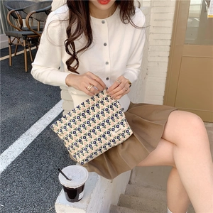 Détail d'une trousse de maquillage en velours côtelé à fleurs tenue par un mannequin