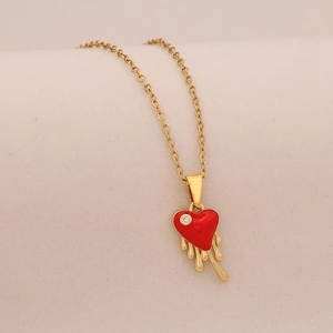 Vue détaillée du collier doré avec pendentif cœur rouge fondant et pierre précieuse