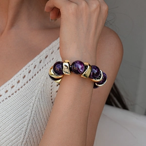 Detail of retro geometric acrylic marbled beads and gold metal segments on a chunky bracelet