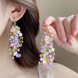 Dettaglio di orecchini a fiori di perline con nappe colorate in viola e rosa