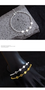 Detailed view of silver and gold beaded bracelets with coin charms on a stone background