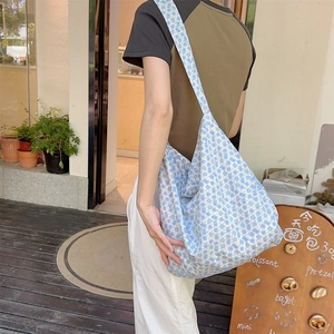 Detailed view of light blue floral canvas tote bag shown in a lifestyle street setting