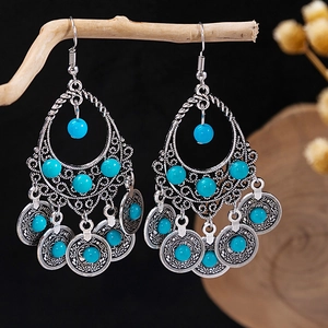 Detail of bohemian silver tassel earrings with turquoise beads hanging on a branch