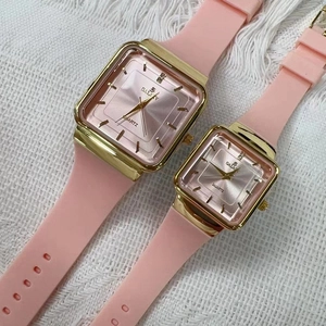 Dettaglio del cinturino in silicone rosa e cassa quadrata dorata su due orologi al quarzo