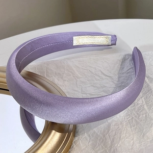 Detail of a purple satin padded headband on a golden vintage frame and crumpled paper
