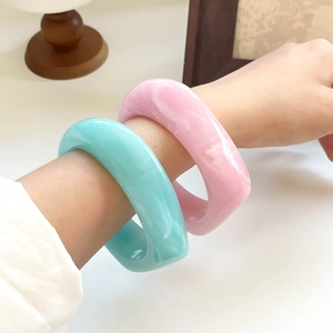 Close-up of pink and blue resin bangles with marble pattern worn on a wrist