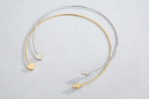 Detailed view of crossover heart and cross open bangles in gold and silver steel