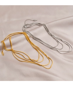 Detail of layered gold and silver snake bone necklaces on elegant champagne silk fabric