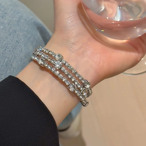 Close-up of triple-layered silver bracelet with sparkling pavé crystals on wrist