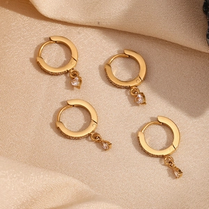 Detail of 18K gold-plated star hoop earrings with zircon drops on soft beige silk