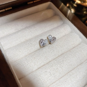 Macro shot of silver heart stud earrings with pearls and zircon in a velvet jewelry box