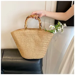 Detail of straw woven tote bag featuring vintage bamboo handles and metal ring accents