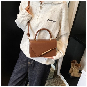 Brown crossbody bag with lychee texture and golden hardware shown in a lifestyle setting