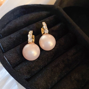 Macro view of large pink pearl earring with crystal gold base in a black velvet jewelry box